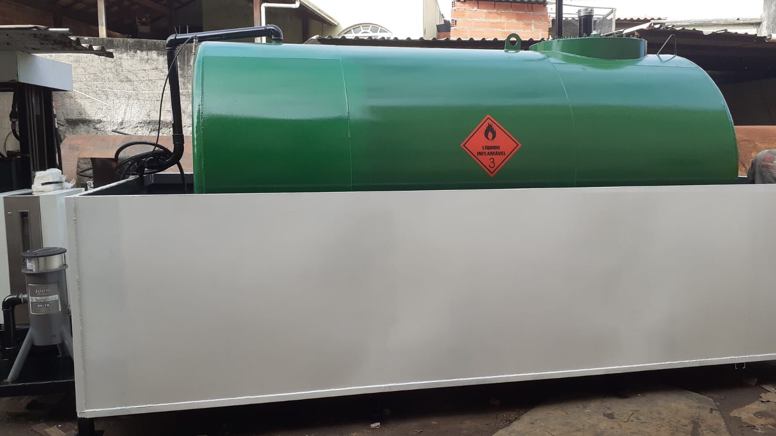 Tanque diesel verde com bacia de contenção e sinalização de líquido inflamável